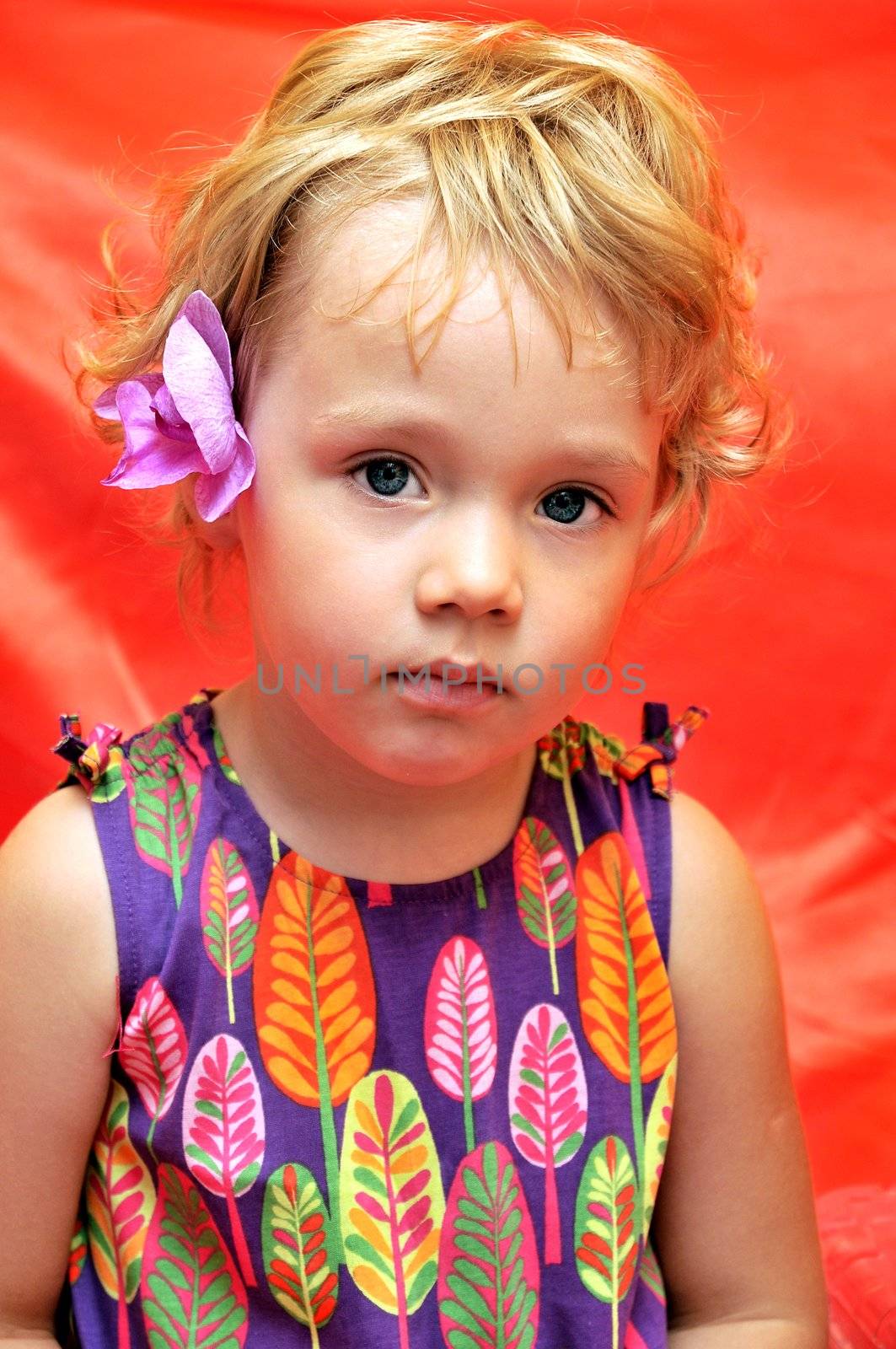 pretty little girl  with orchid in her hair over red 