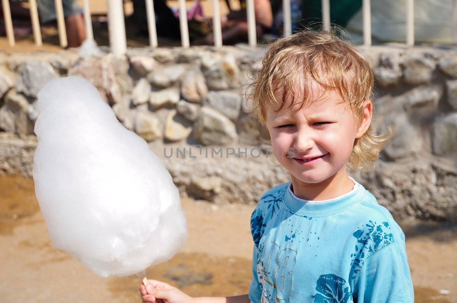 little boy is enjoying cotton candy  in hot summer day