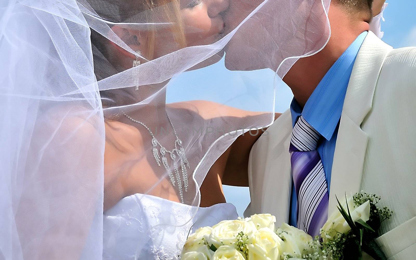 wedding passionative kiss of bride and groom under blue sky