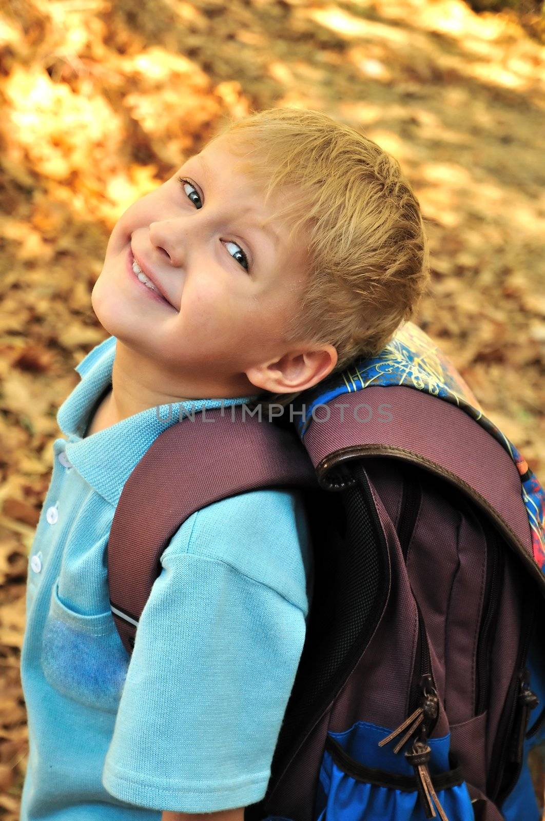 Child resting in a park amongst autumn leaf fall after school