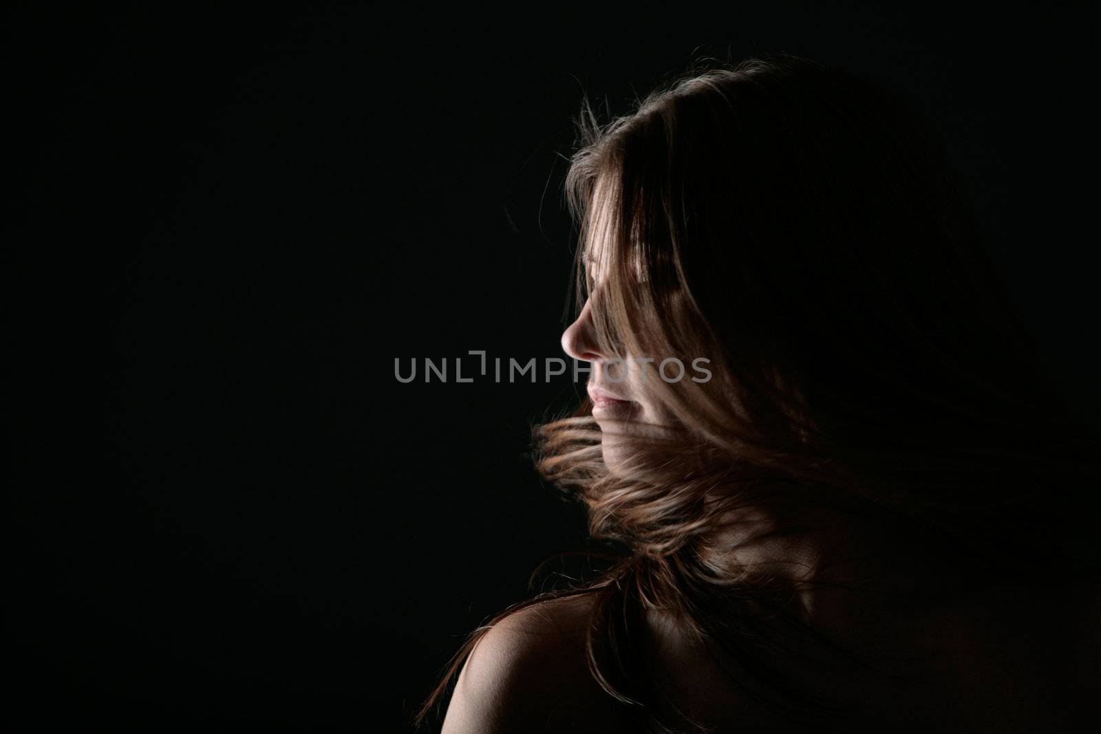 Young woman portrait on the wind with black background