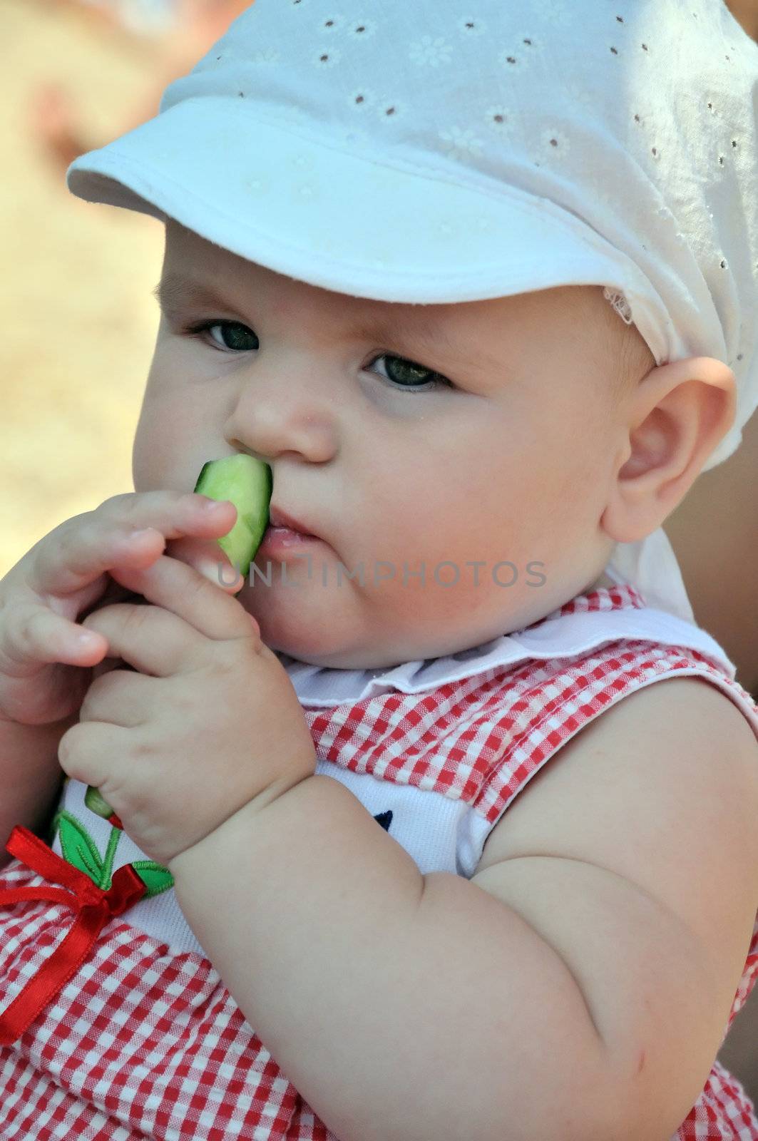 little baby girl is enjoying peace of cucumber