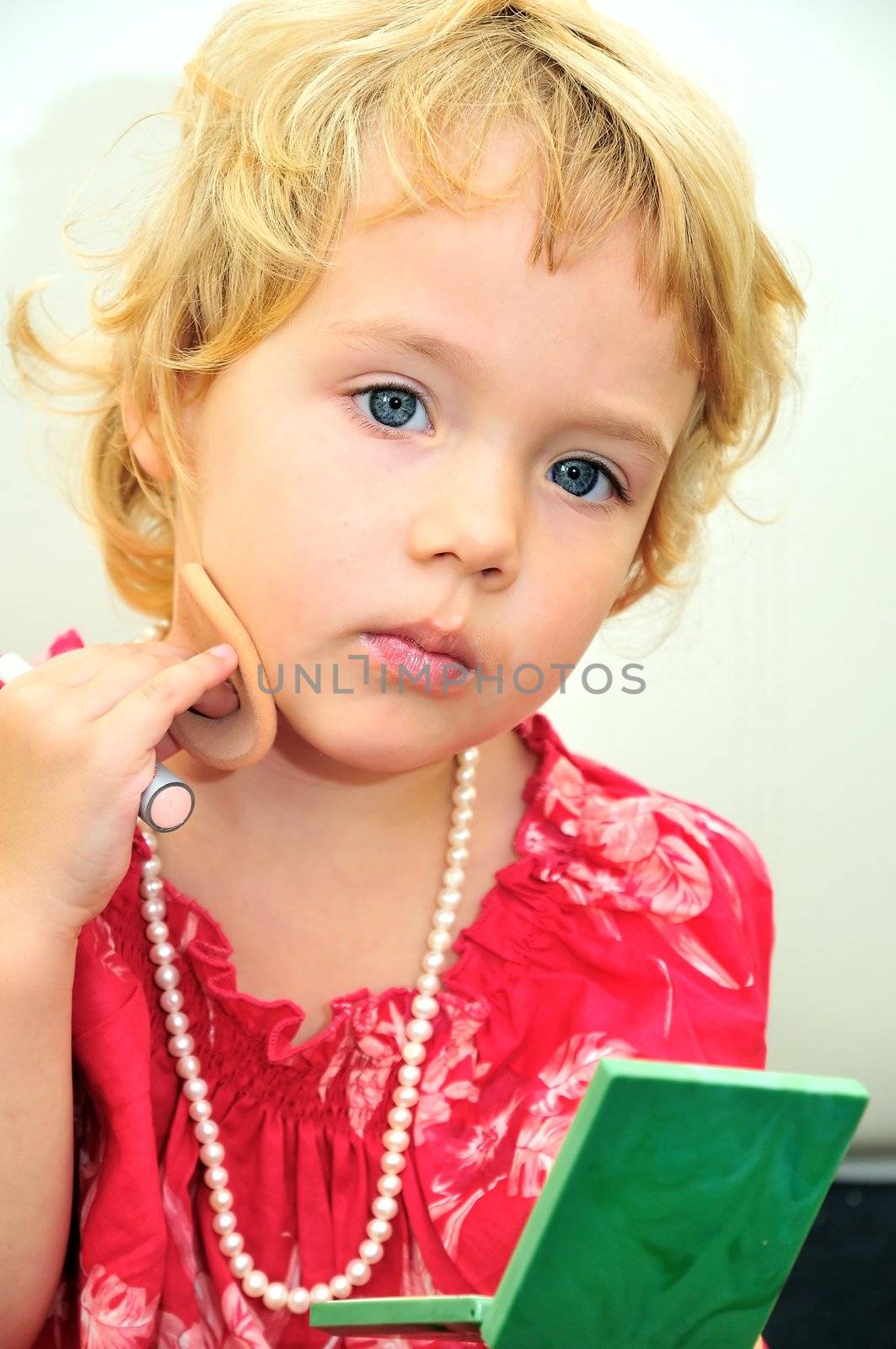 little girl using powder and lirstick she is wearing necklace
