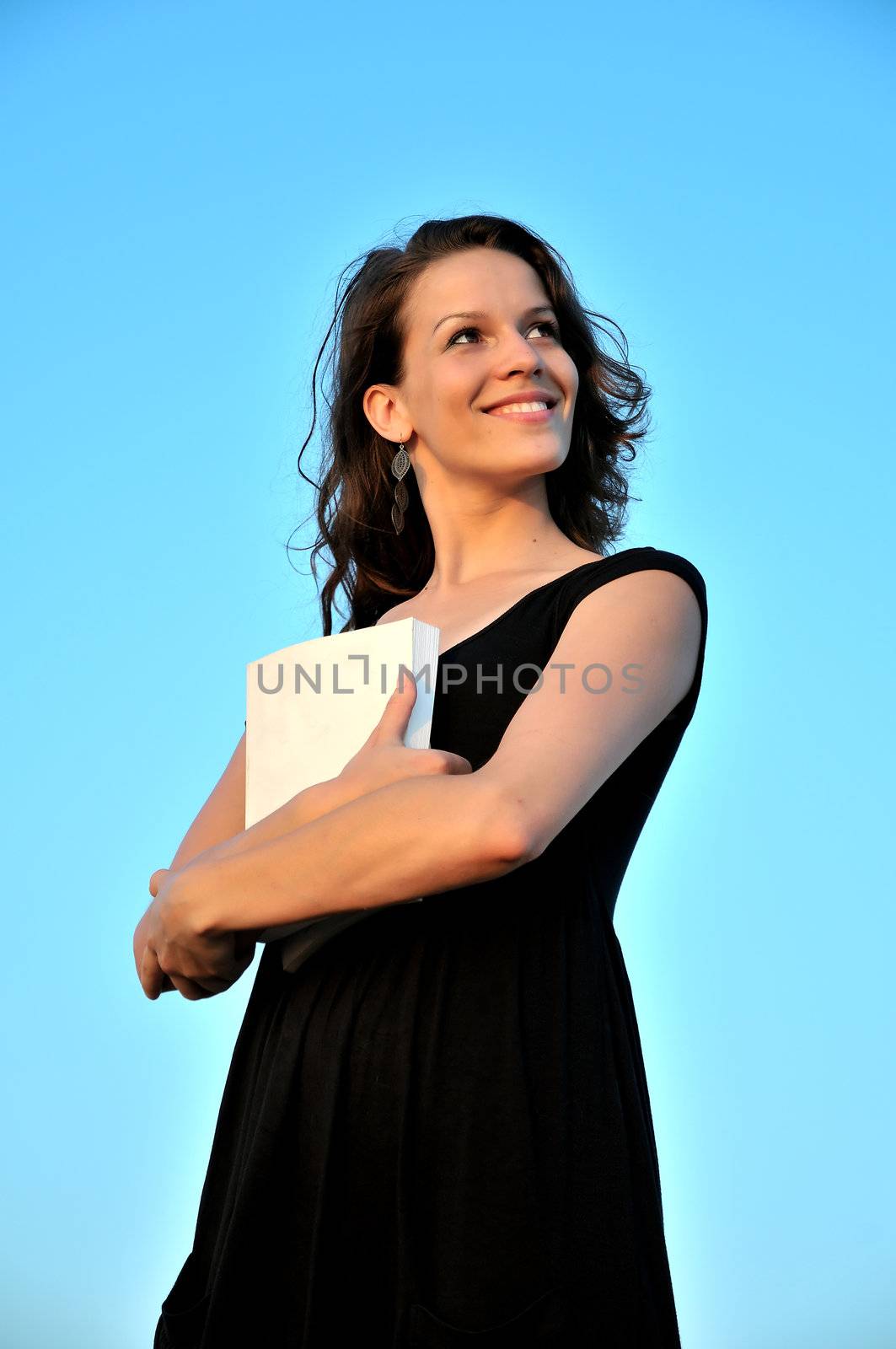 beautiful girl taking book ( it's possible to write anything  on it) over blue background 