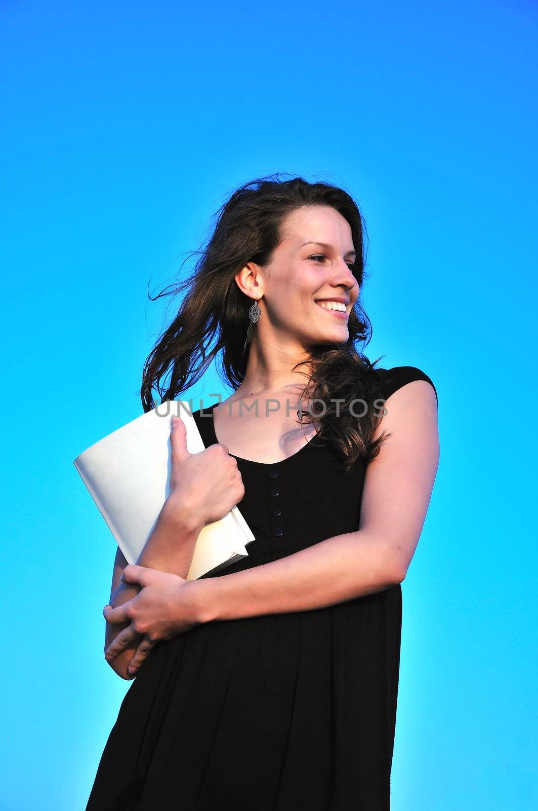 beautiful girl taking book ( it's possible to write anything  on it) over blue background