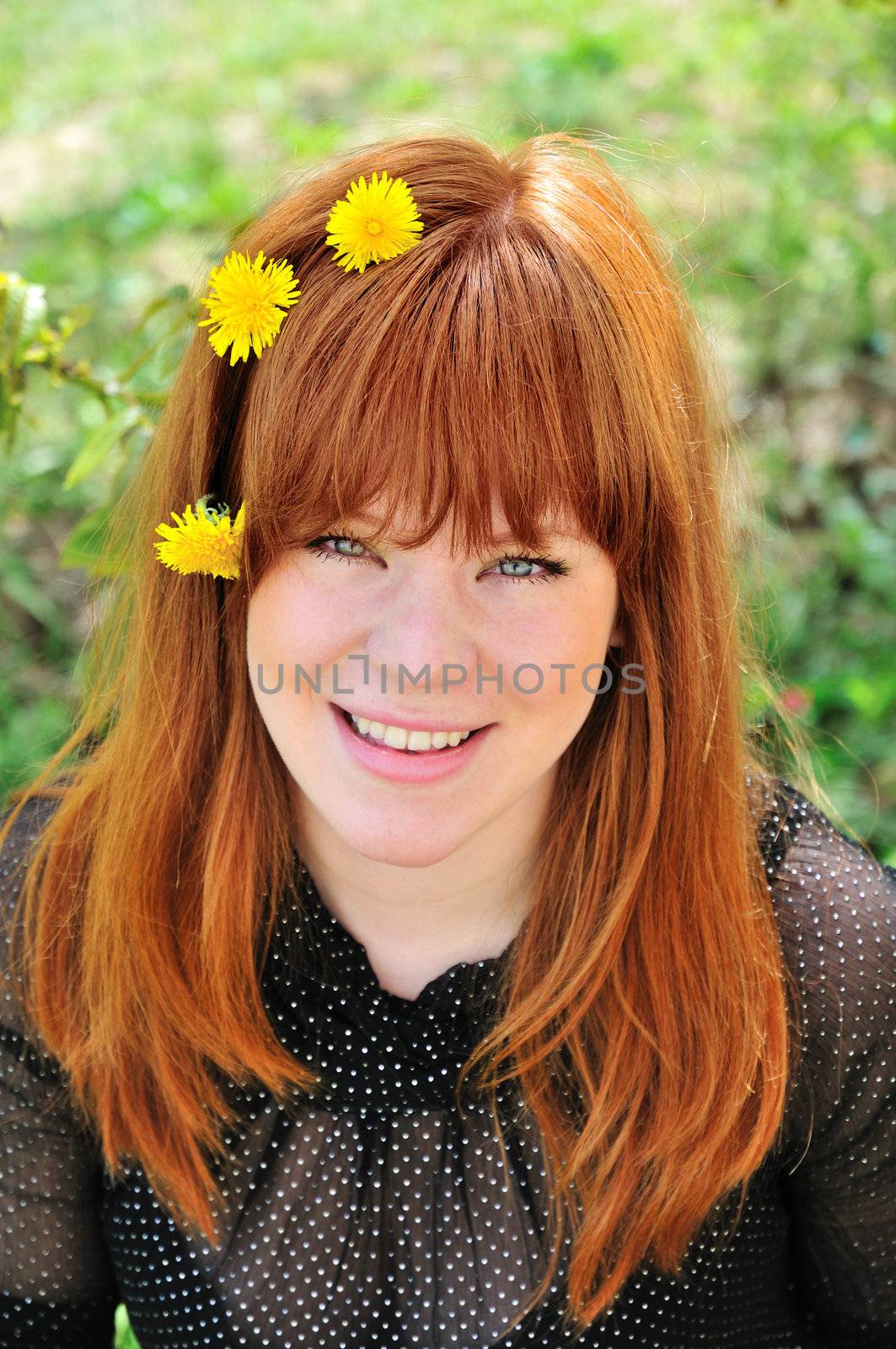Beauty redheaded girl with dandelions in her hair, green eyes red hair green leaves.