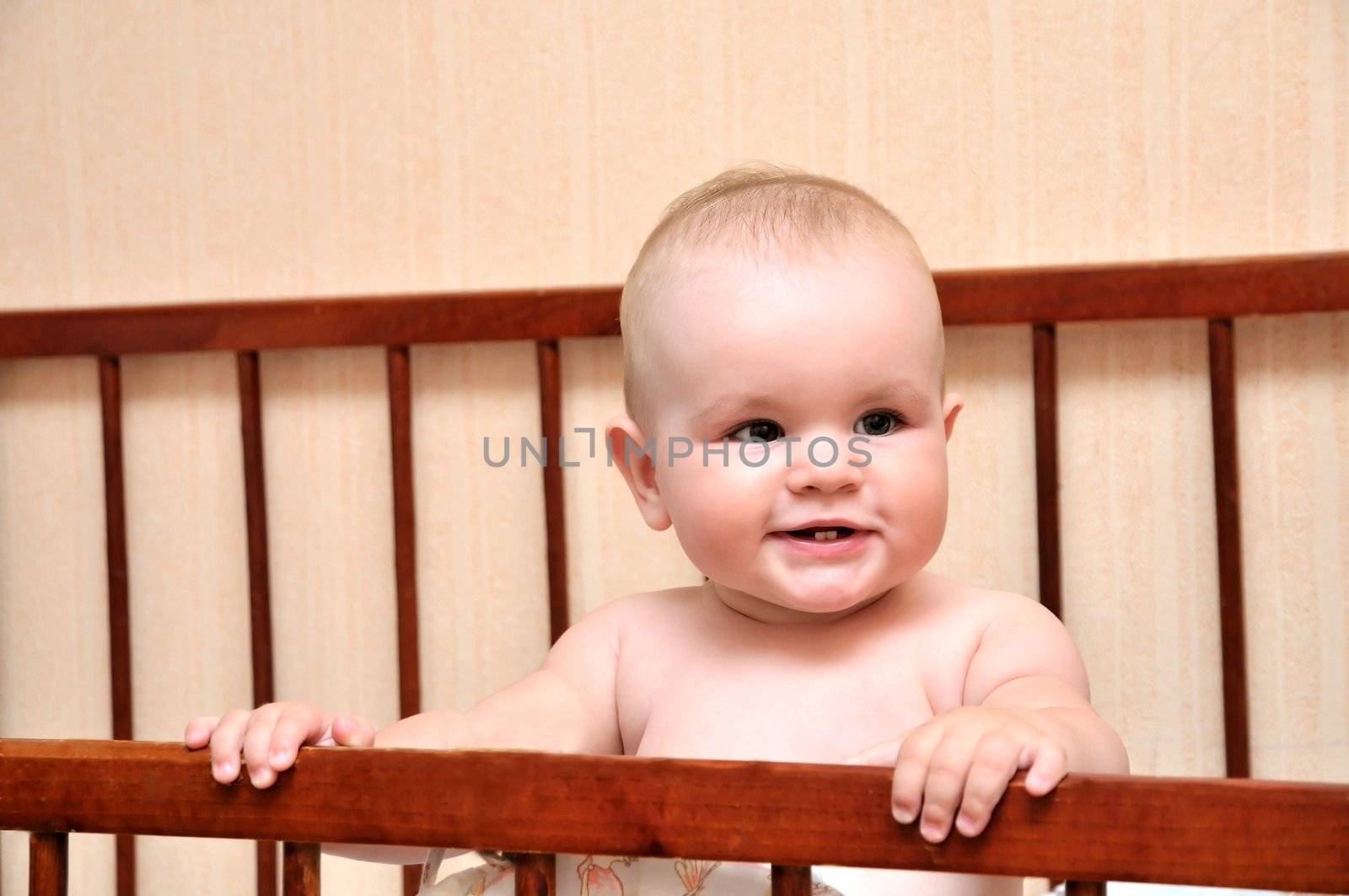 funny baby holding bed grating and smiling, hey first tooth is visible