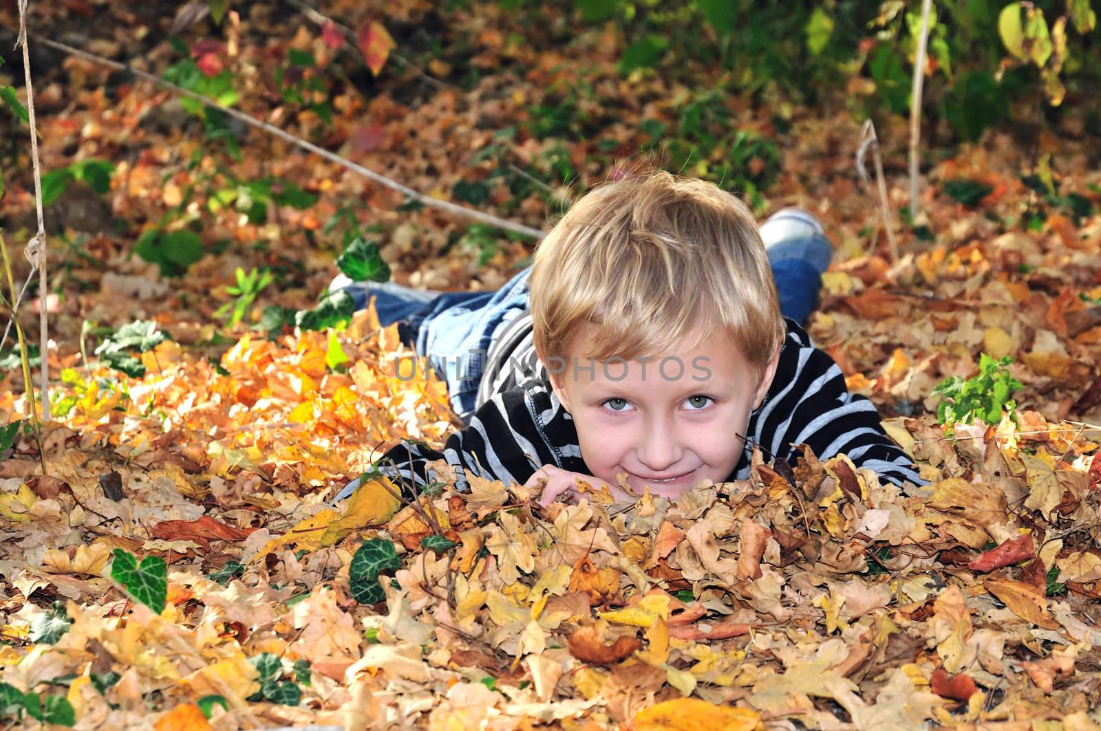 boy is laying in the forest in fallen leaves