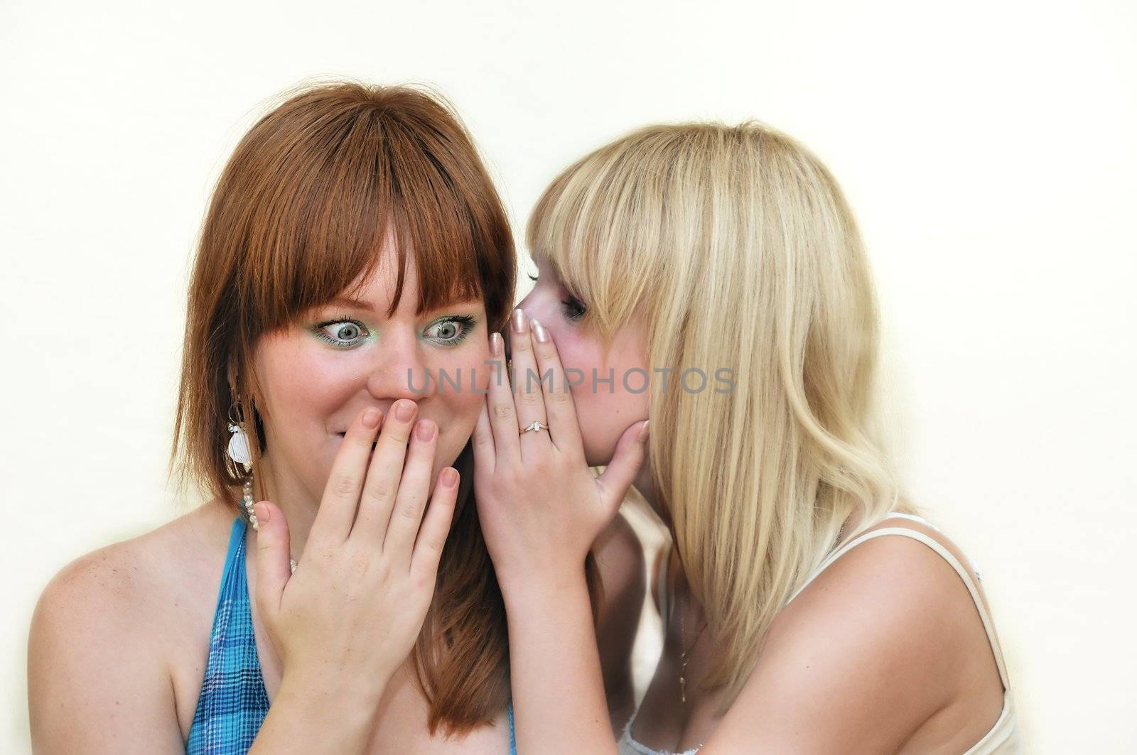   two young girlfriends whispering about something