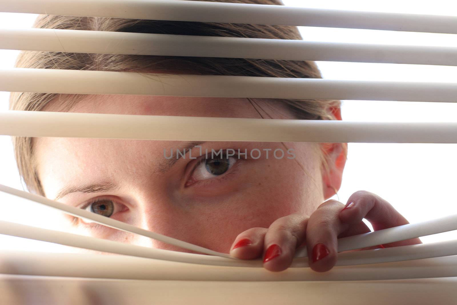 curious girl looking through roller-blind