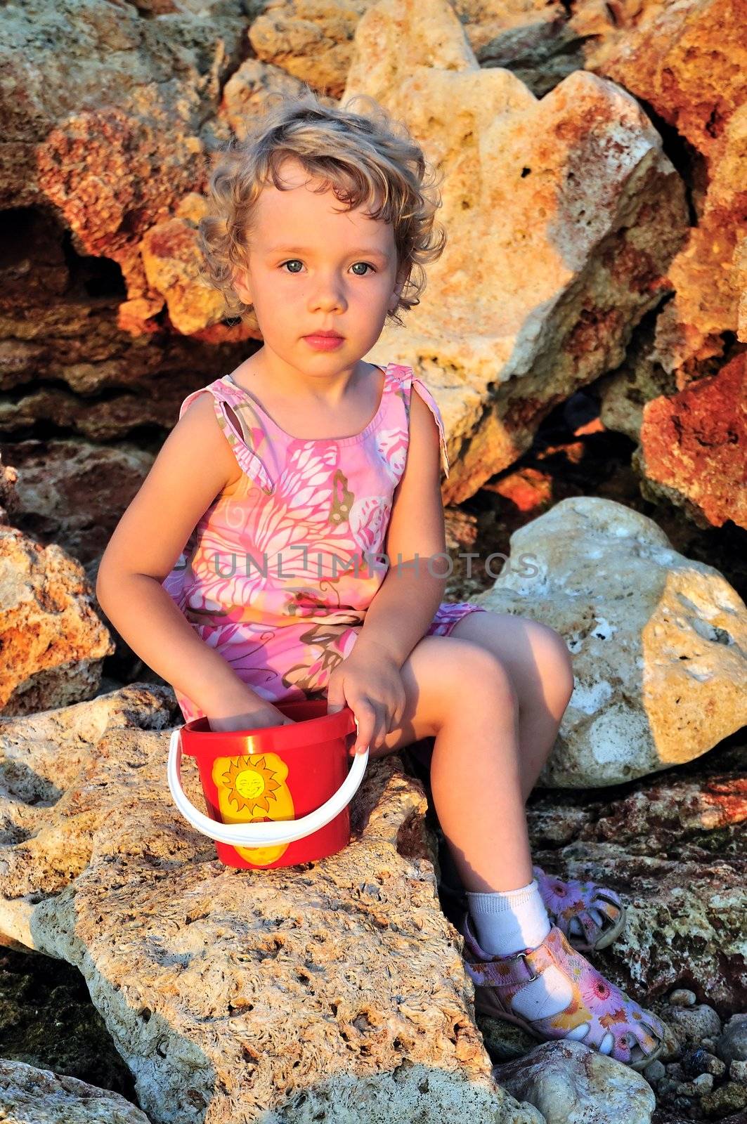 little girl is playing with can  on the cliffed beach