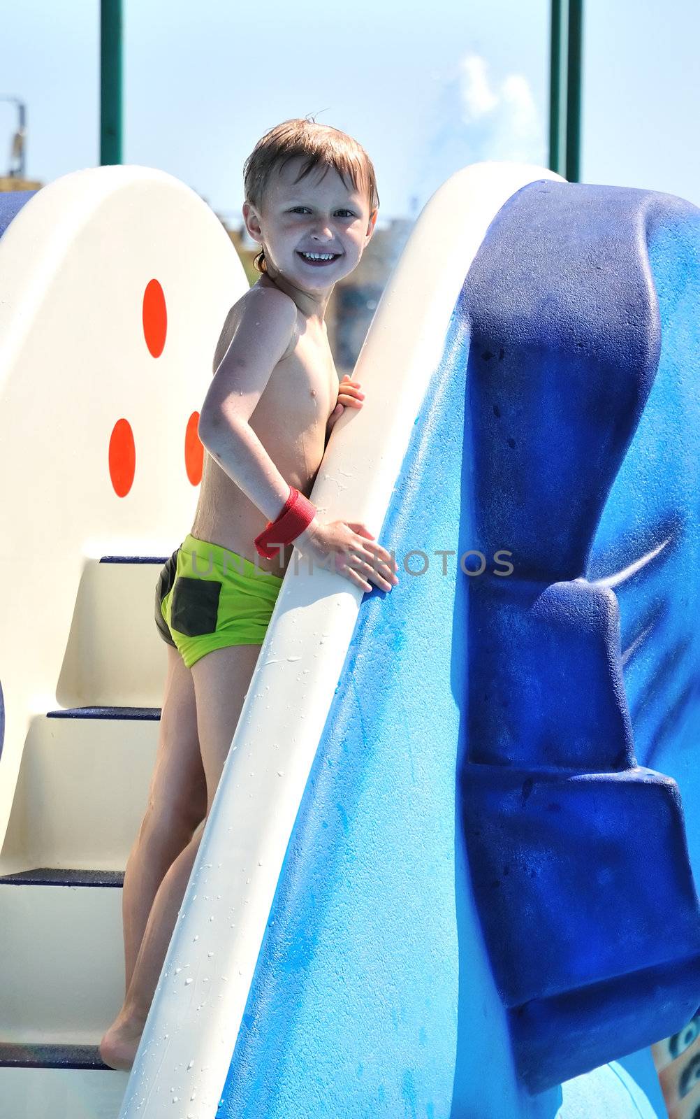 little boy wearing swim suit climbing water slide