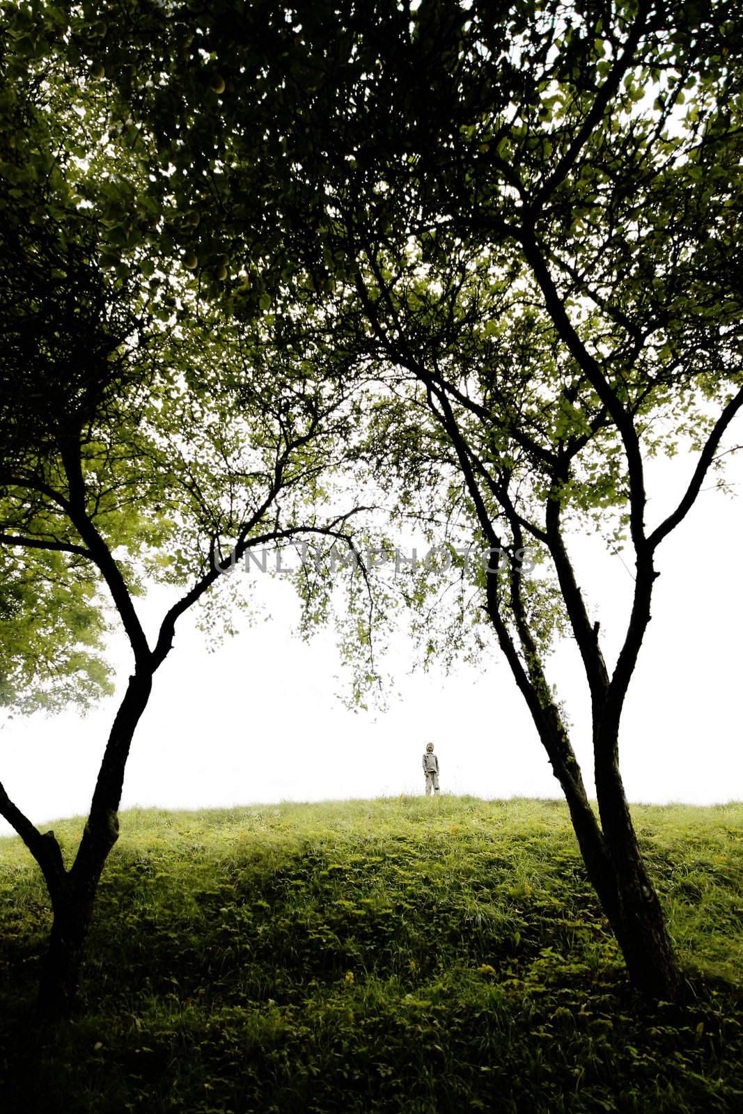 young boy sings on a green hill, wide angle perspective