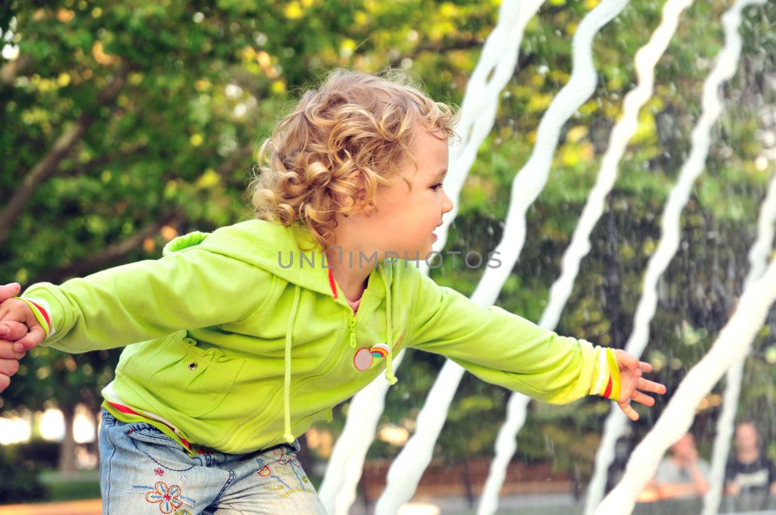 little blonde curved girl touching water of 	 fountain