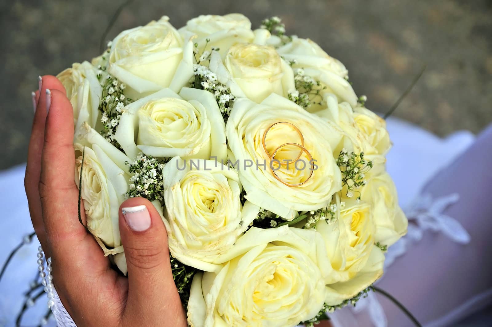 bride holding wedding flowers (roses) and gold rings 
