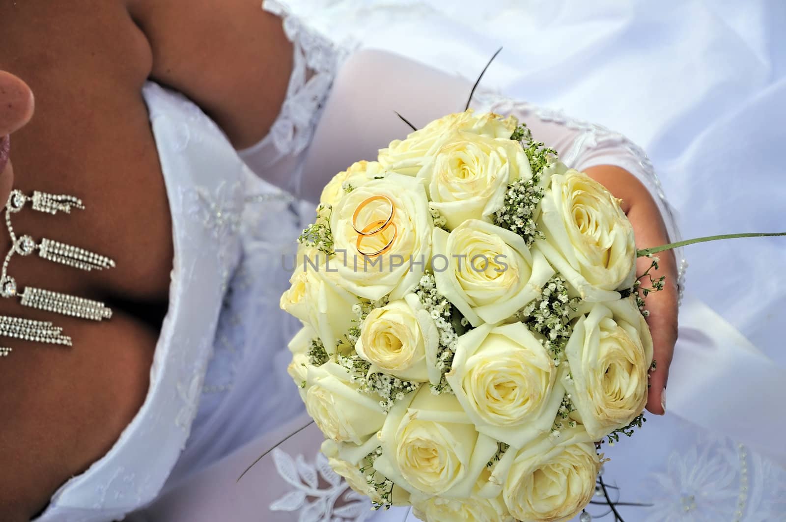 bride holding wedding flowers (roses) and gold rings 