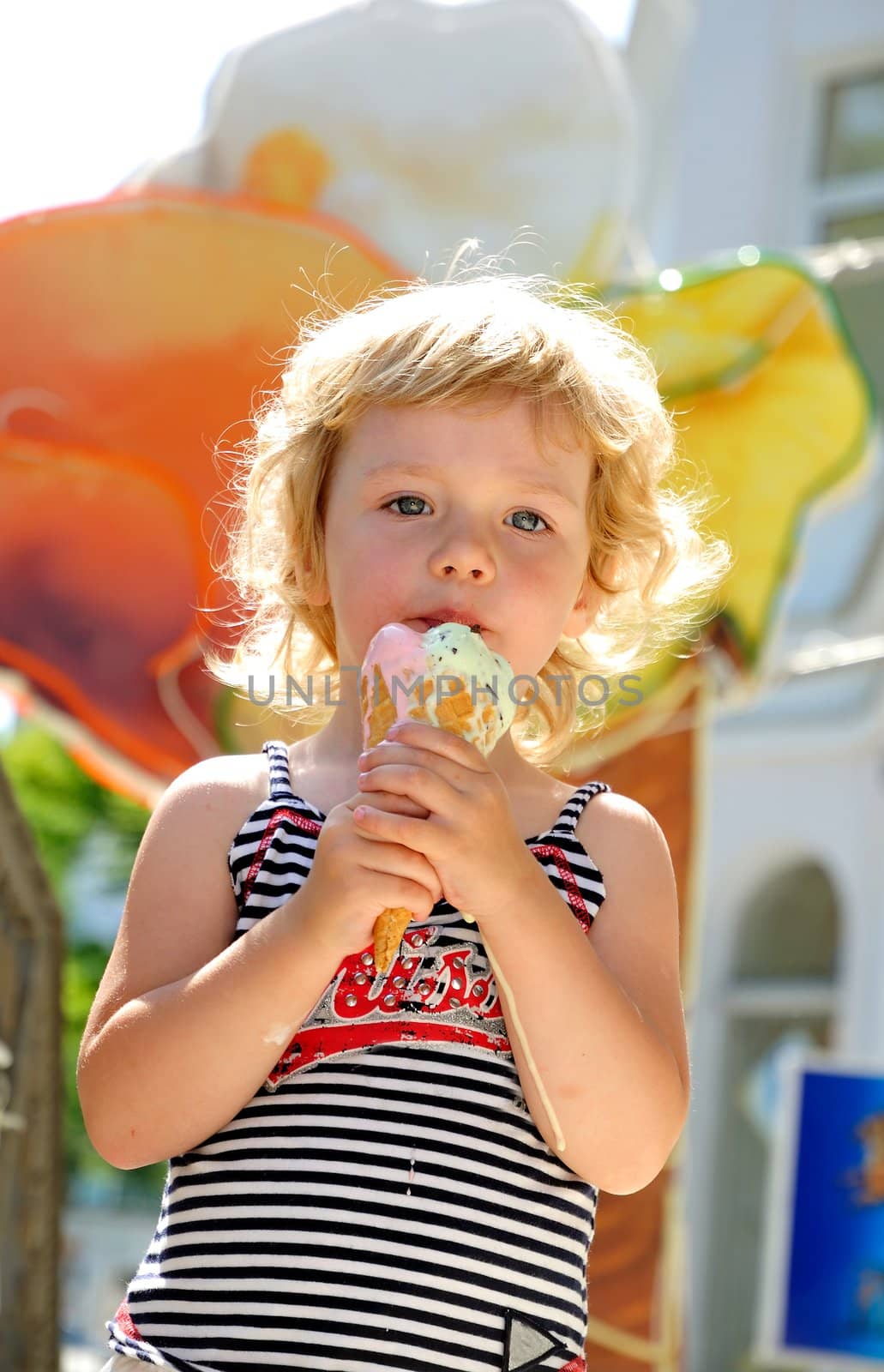 little girl outdoors eating huge ice cream cone
