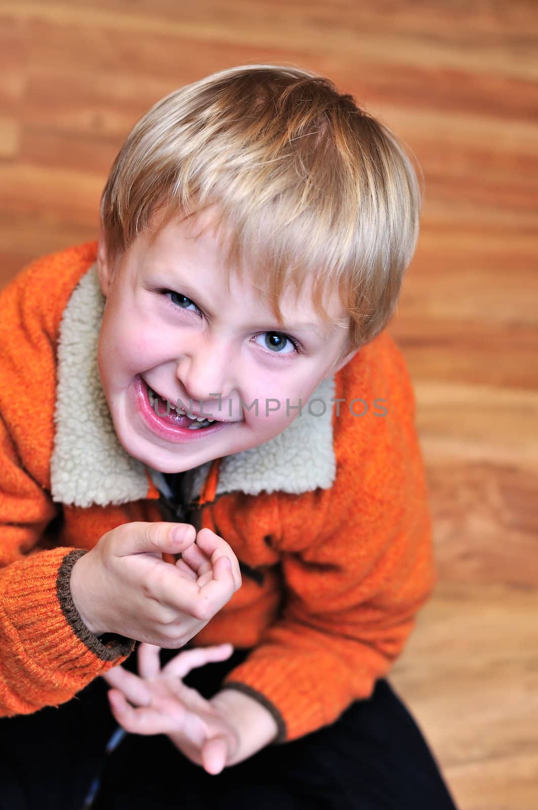 Little blonde boy making grimace and sitting on the deck 