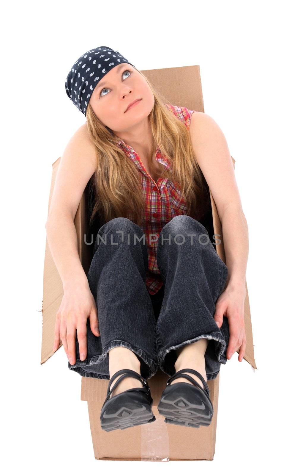 Girl sitting in a cardboard box, looking up. Isolated on white.