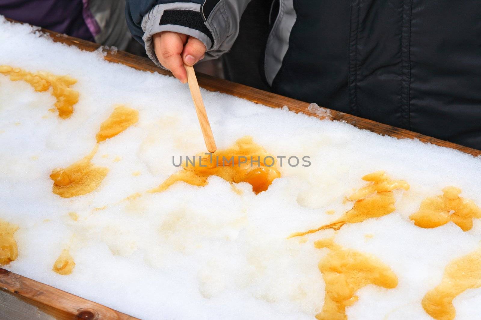 Child putting on a sick maple taffy, traditional treat in Quebec, Canada.