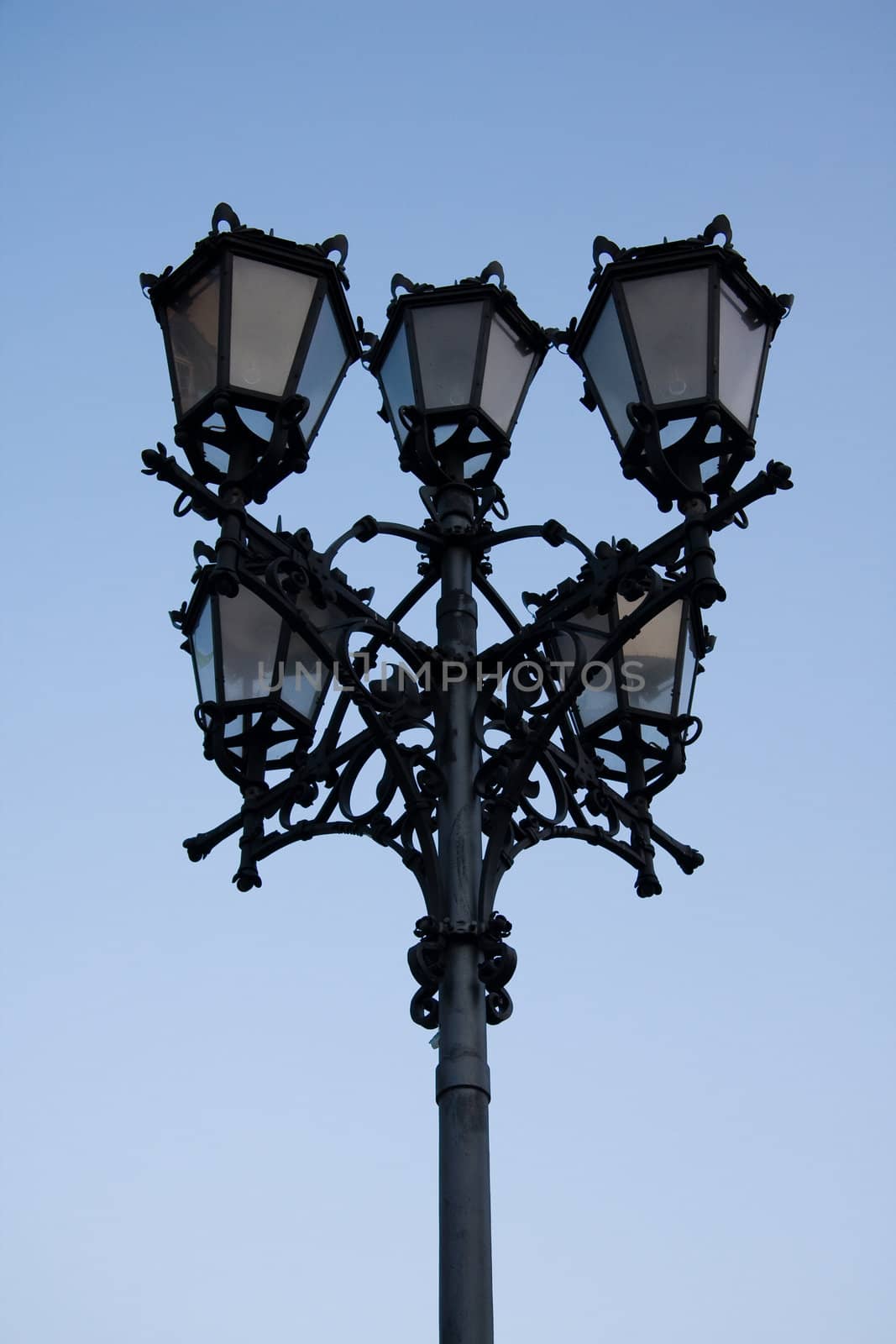 Antique style lamp post against blue sky background.