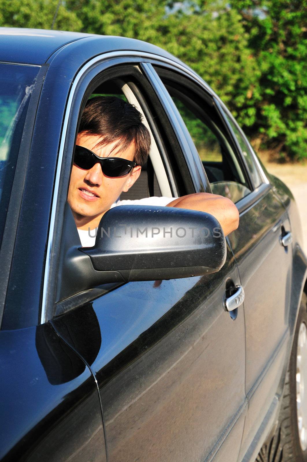 young man wearing sun glasses in the dark car