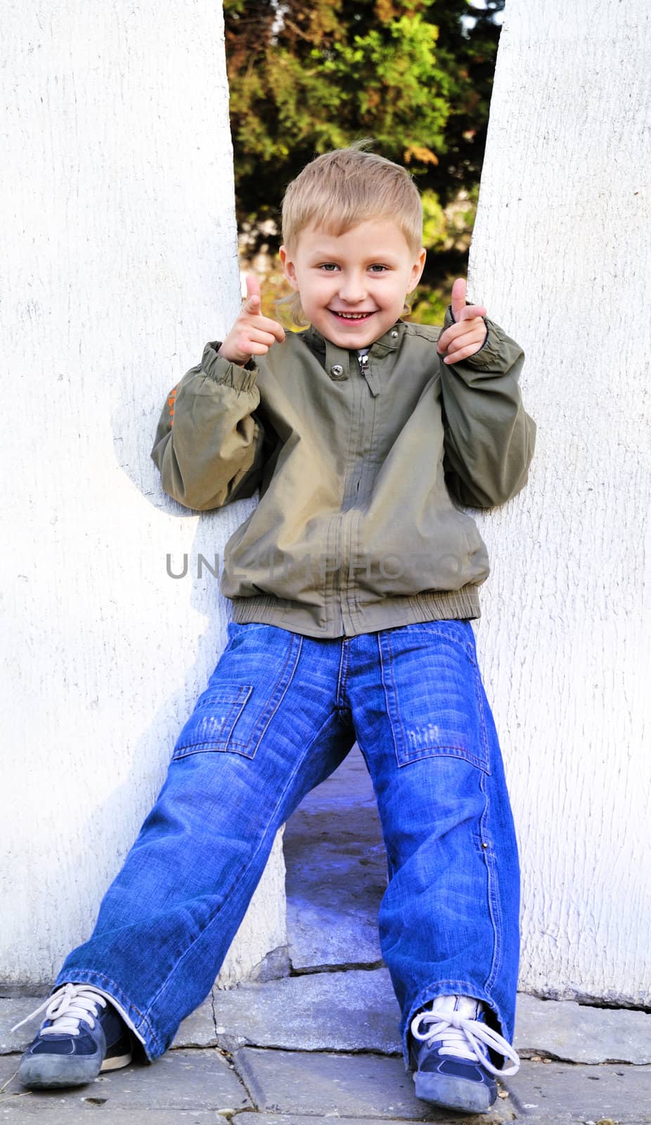 cute boy wearing jeans  showing his fingers like a gun
