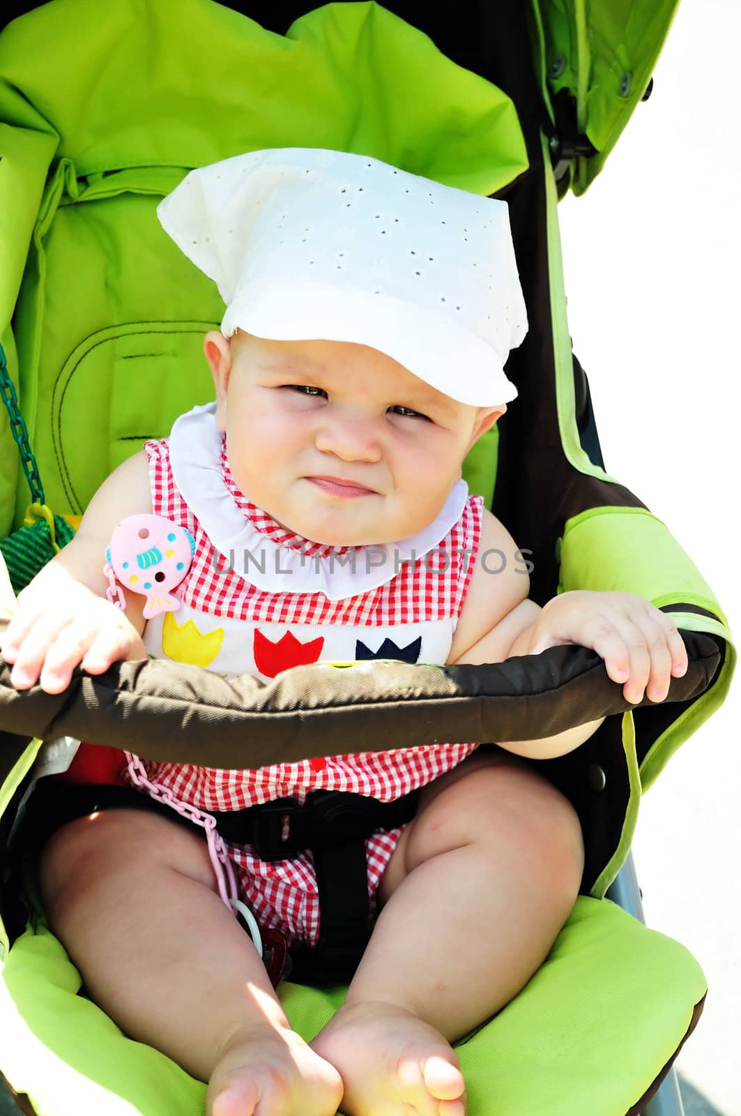 serious  baby girl sitting in the storller