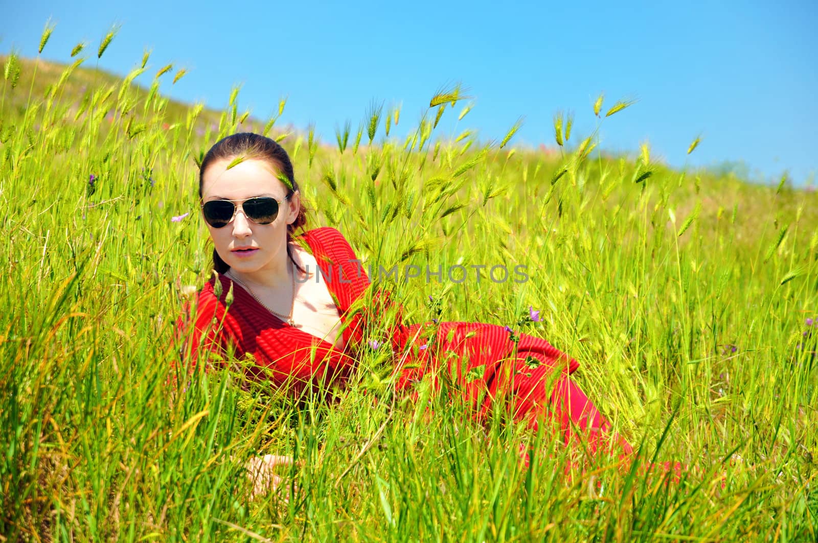 pretty girl laying in green grass in summer time