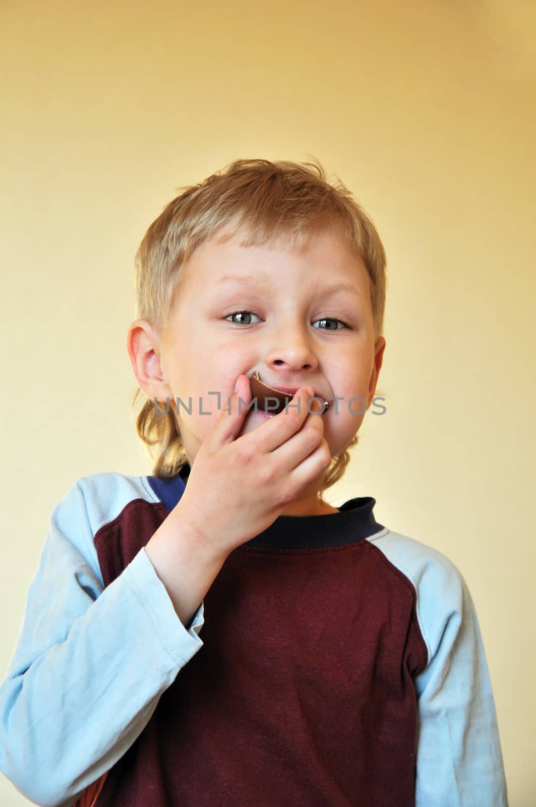 little blonde  boy is eating chocolate egg