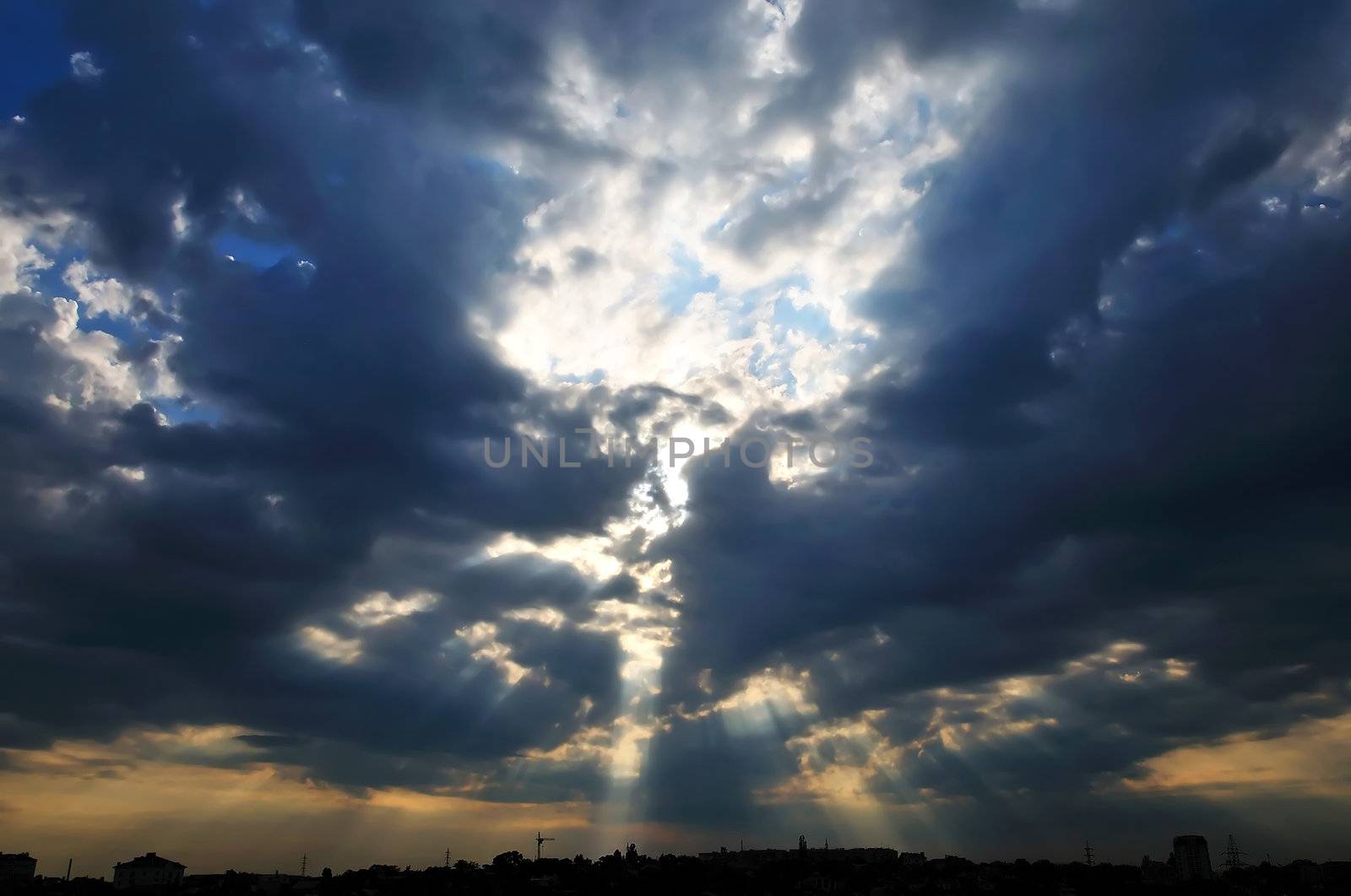 Dark clouds and little peace of blue sky with sunlight under the town