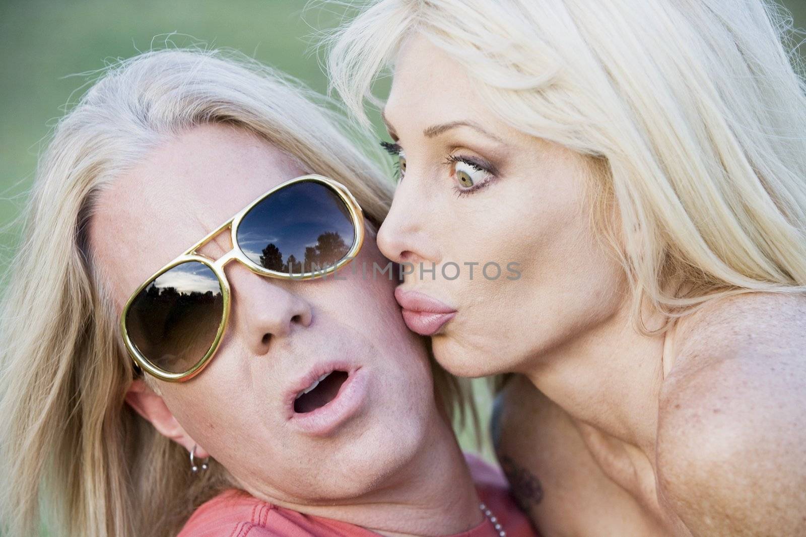 Woman with big eyes kissing a surprised and pleased man