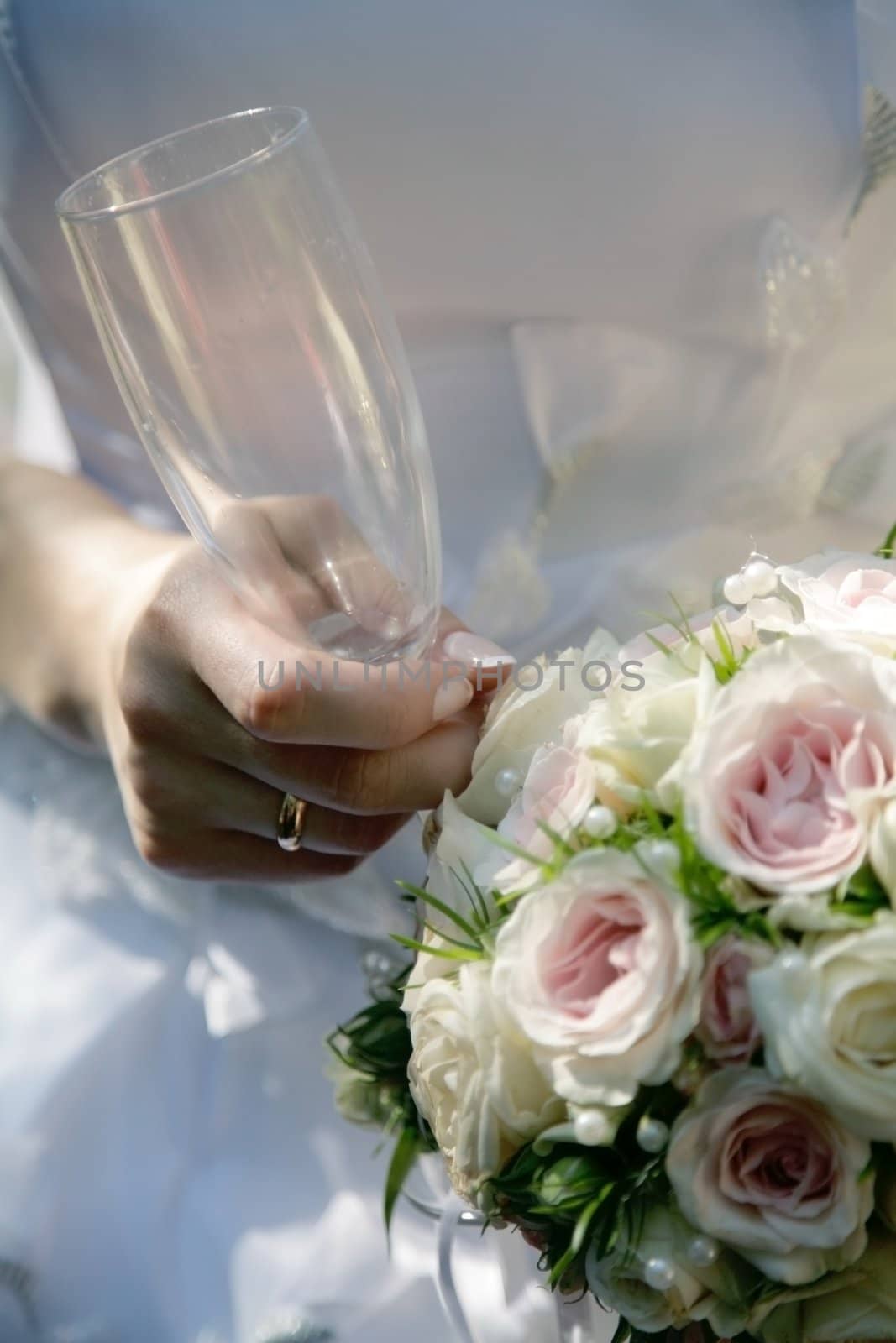 Brides hands with empty glass and roses