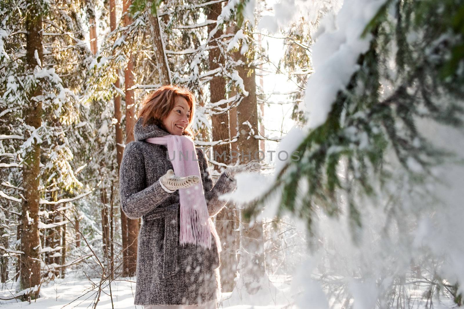 Happy red-haired woman having fun on winters day in forest.