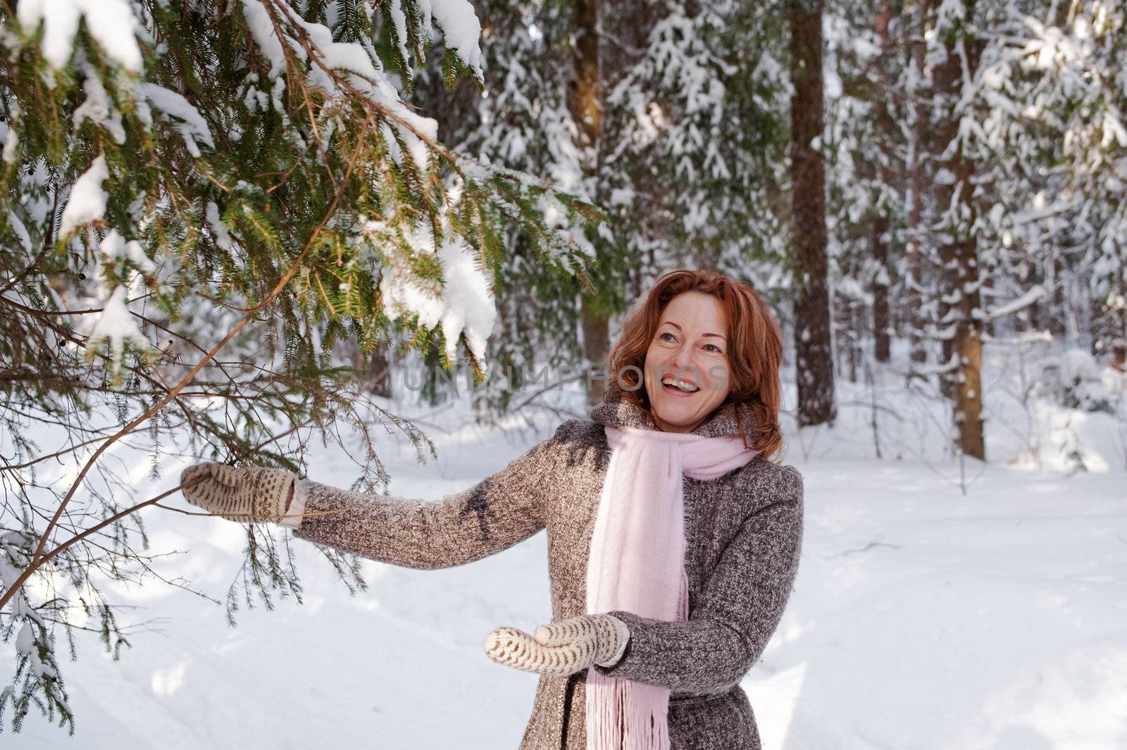 Happy red-haired woman having fun on winters day in forest.