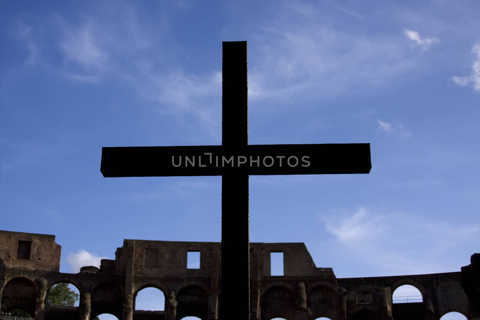 Silhouette of cross over blue sky in colosseum