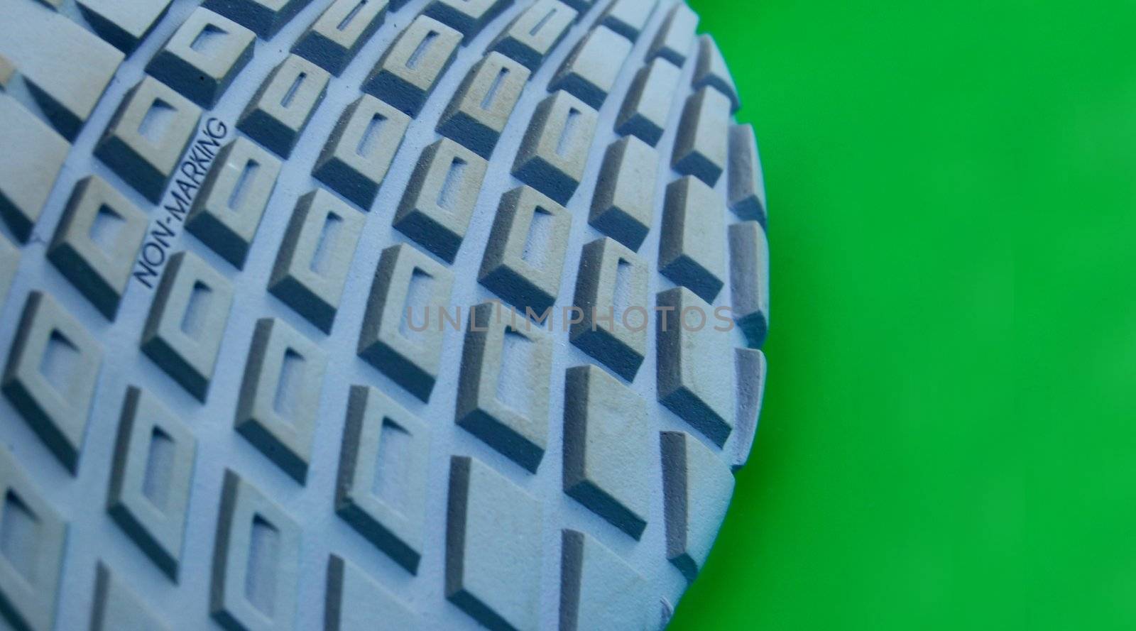 macro pattern of rubber sole of sneakers against green