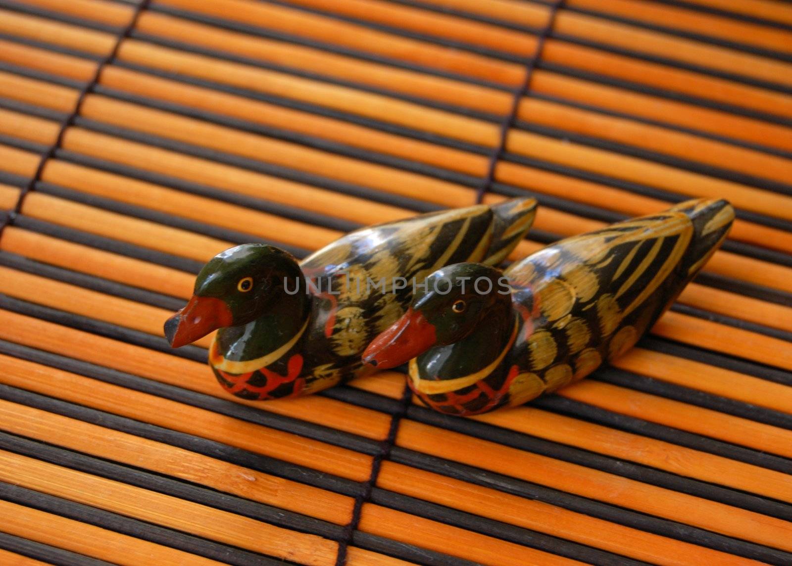macro pattern of yellow and black bamboo mat and two ornate duck (chopsticks stands)