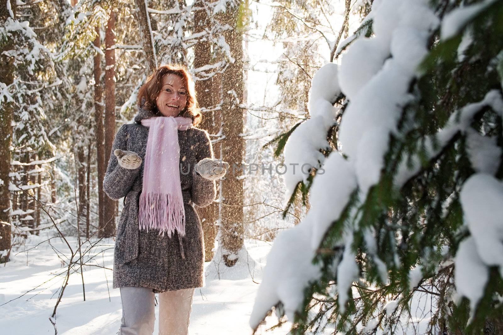 Happy red-haired woman having fun on winters day in forest.