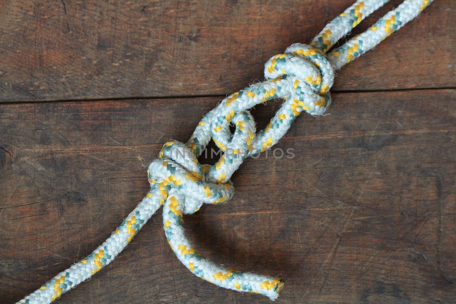 Two ropes constrained with knots lying on wooden background