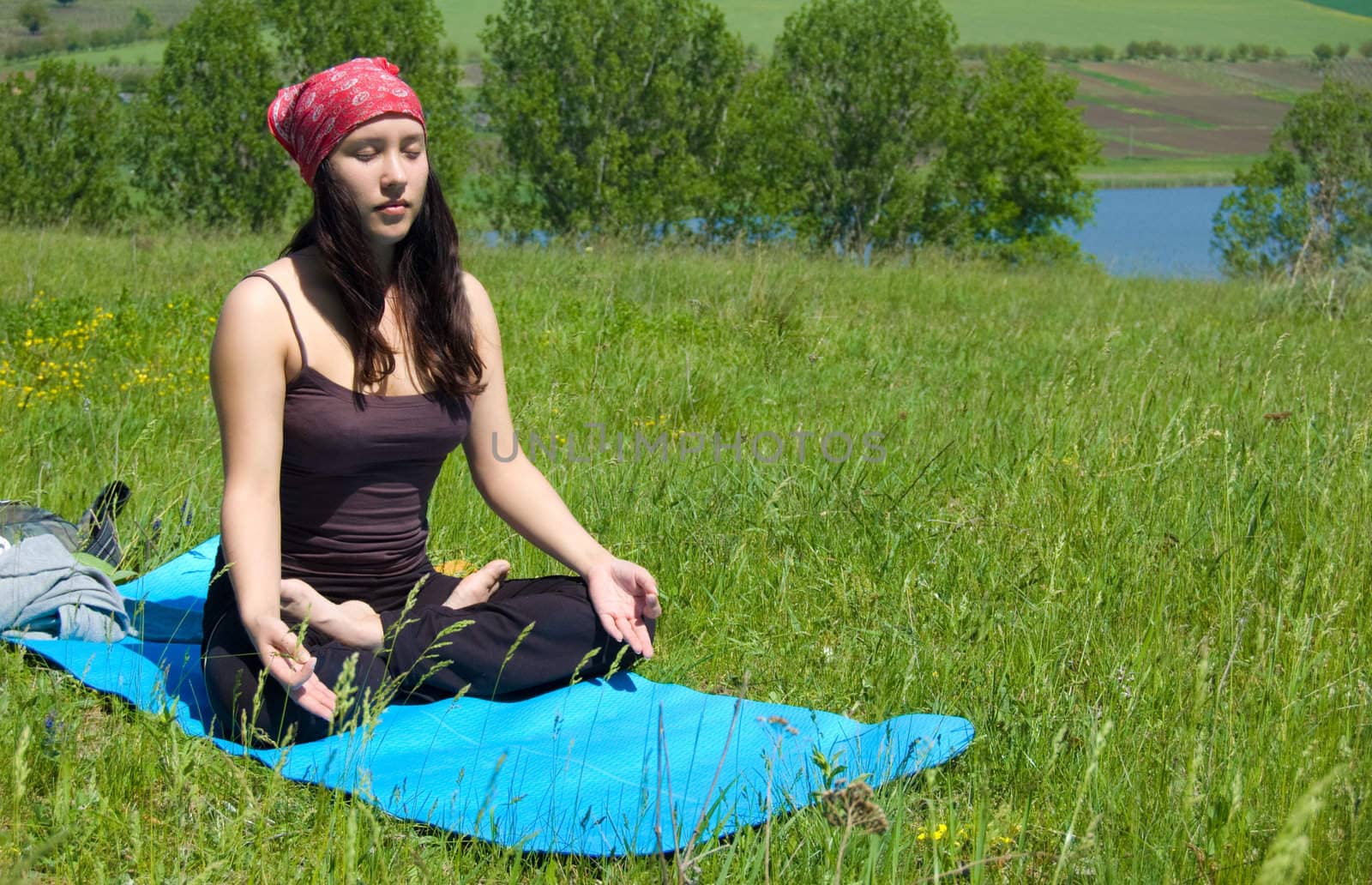 Woman practicing yoga on a green meadow