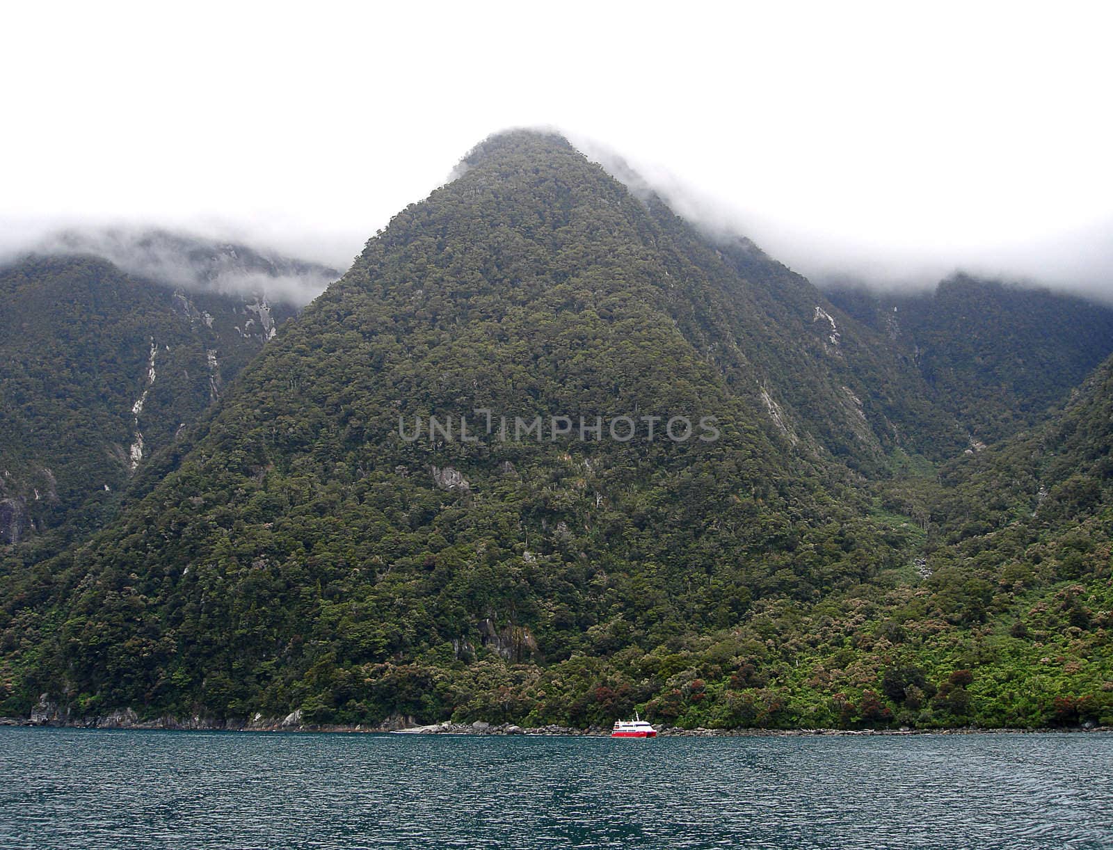 Tourist Boat sailing past Mountains within Milford Sound, New Zealand.  Te Wahipounamu World Heritage Site