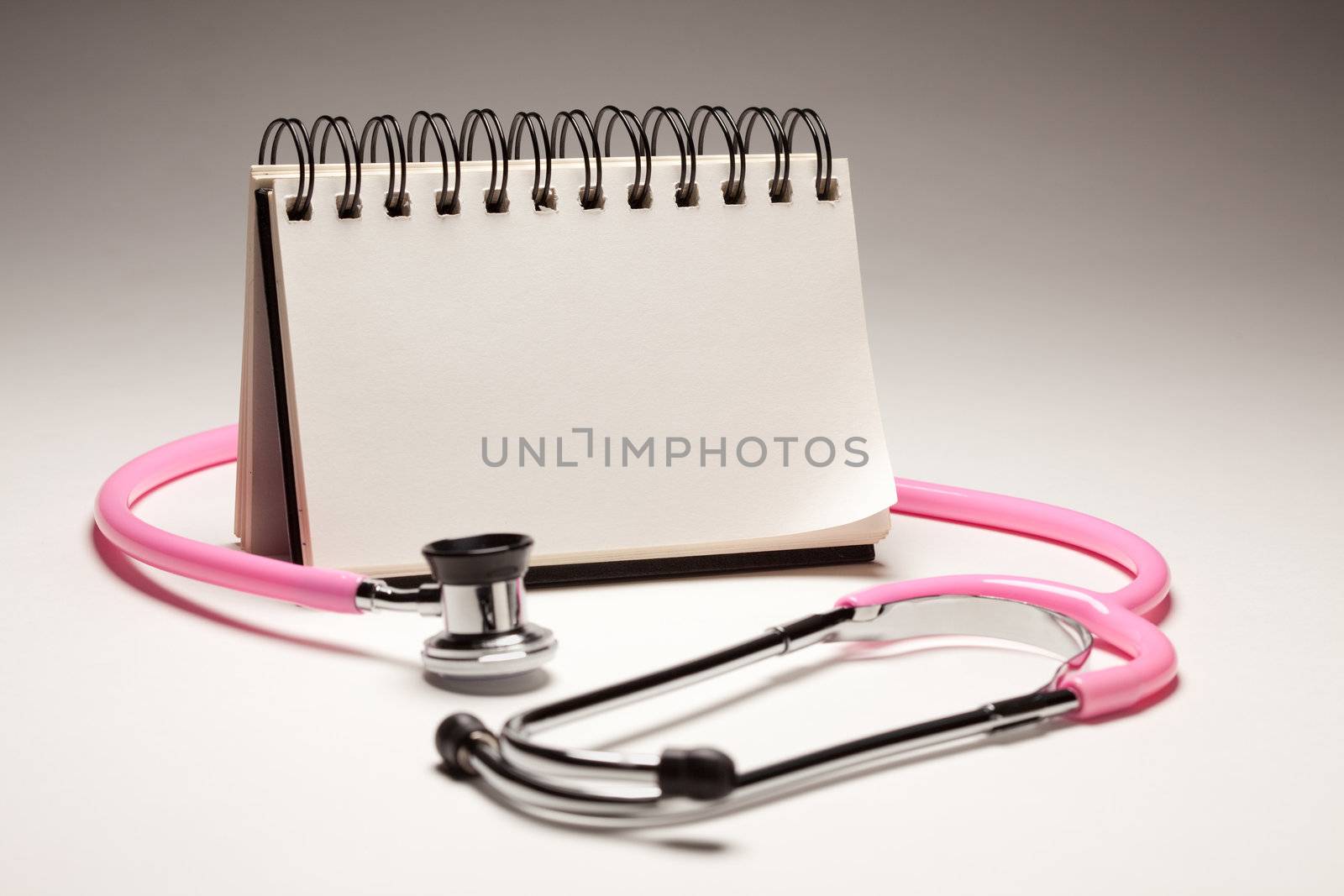 Blank Spiral Note Pad and Pink Pediatric Stethoscope on Gradated Background.