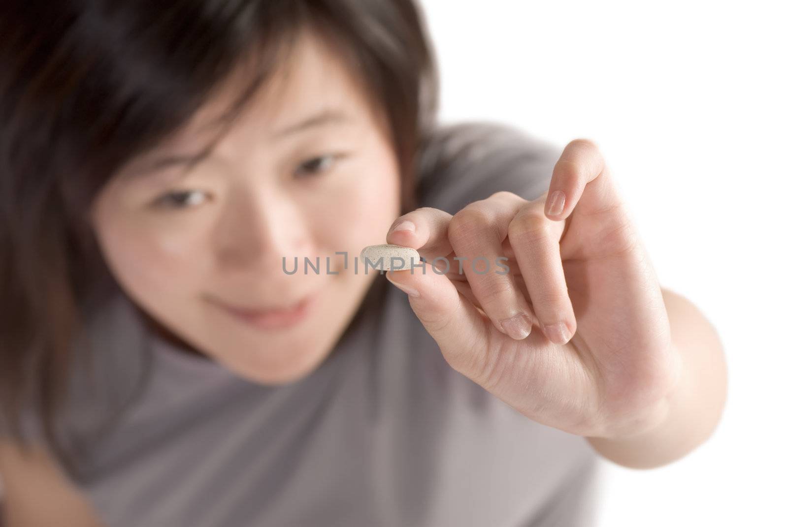 Woman with pill on white background, focus on pill.