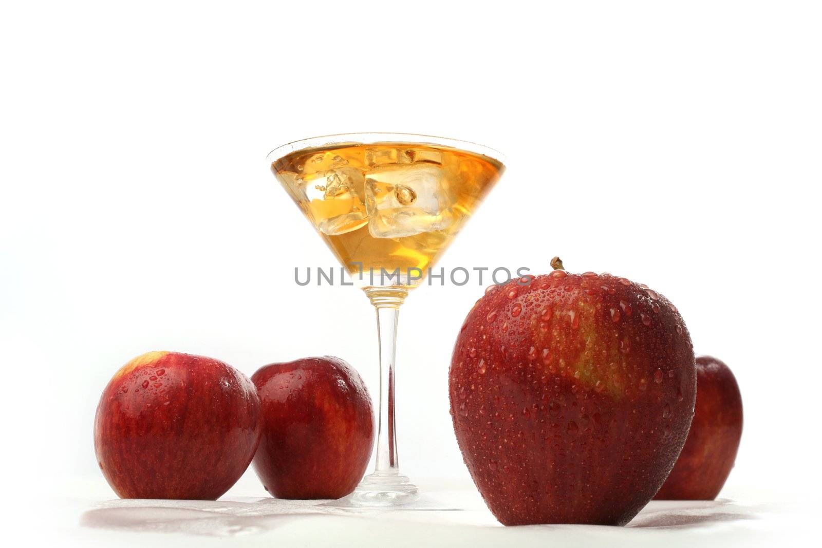 glass of apple juice and ice cubes, surrounded by red apples