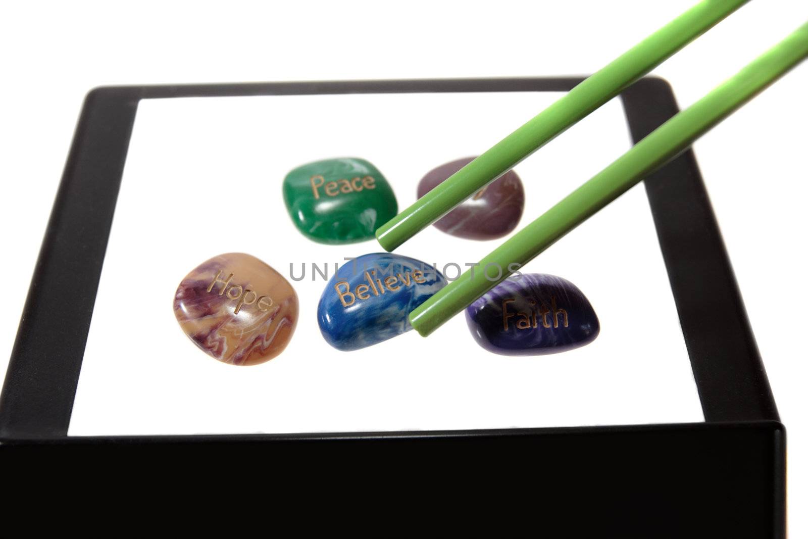 five stones inscribed hope joy peace faith and believe being picked up by chopsticks showing have belief in the new chinese year