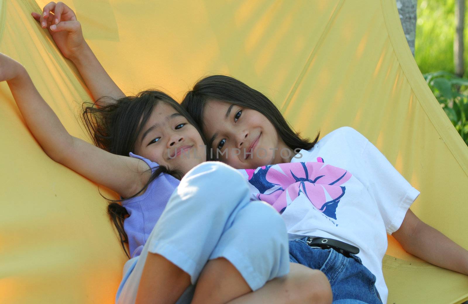 Two girls swing on hammock by jarenwicklund