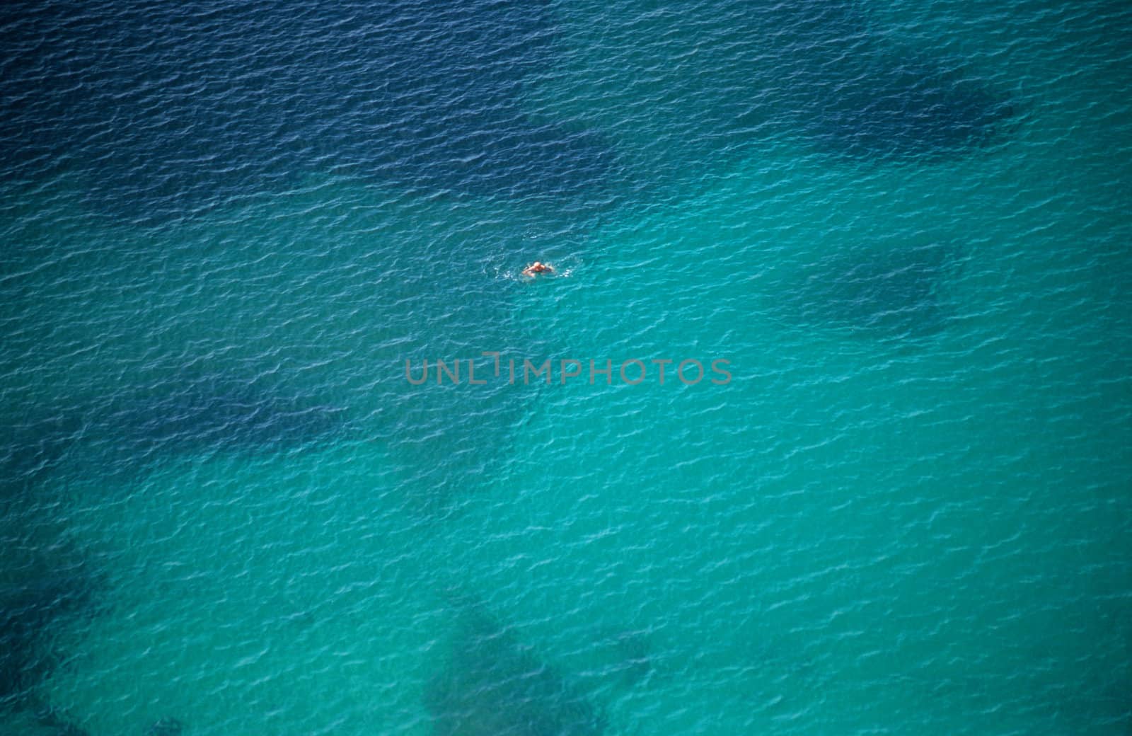A solitary swimmer paddles in the Mediterranean sea.