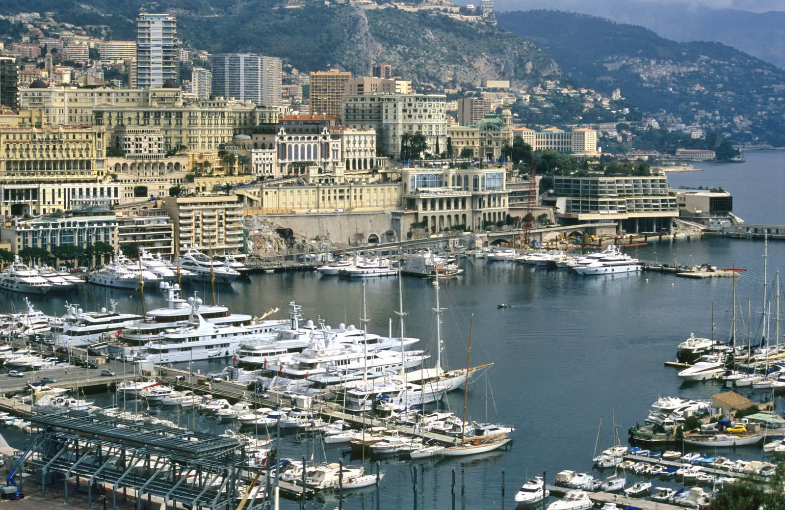 Luxury yachts dock in Monaco, home of the Monaco Grand Prix and the Monte Carlo Casino visible in the background.