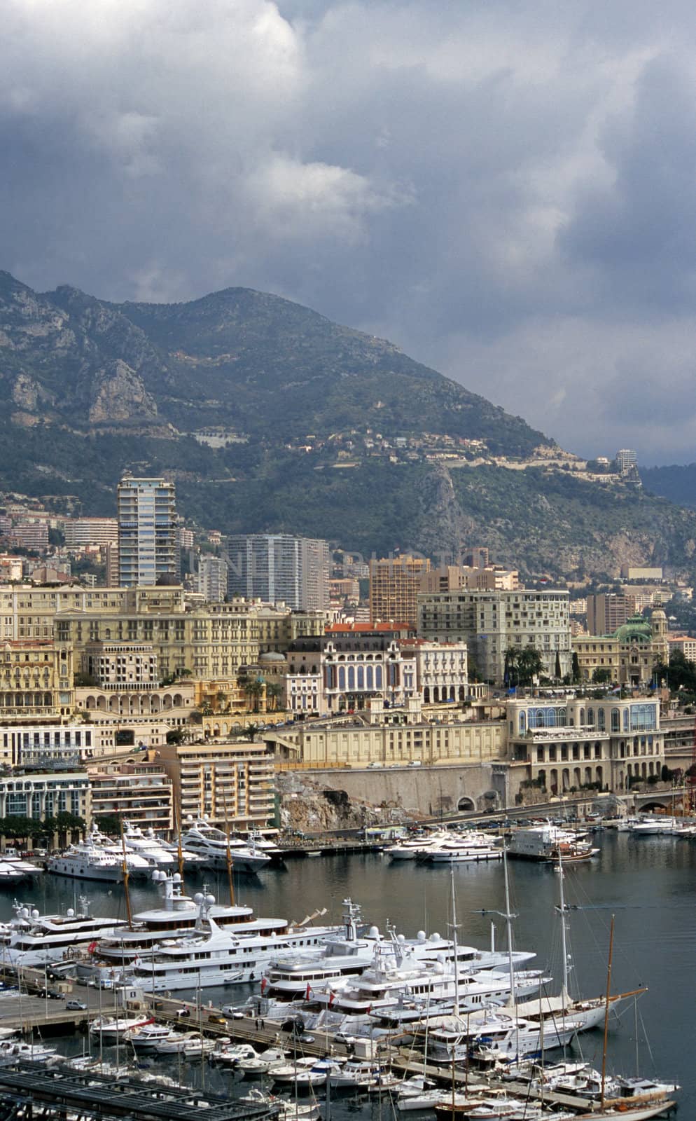Luxury yachts dock in Monaco, home of the Monaco Grand Prix and the Monte Carlo Casino visible in the background.